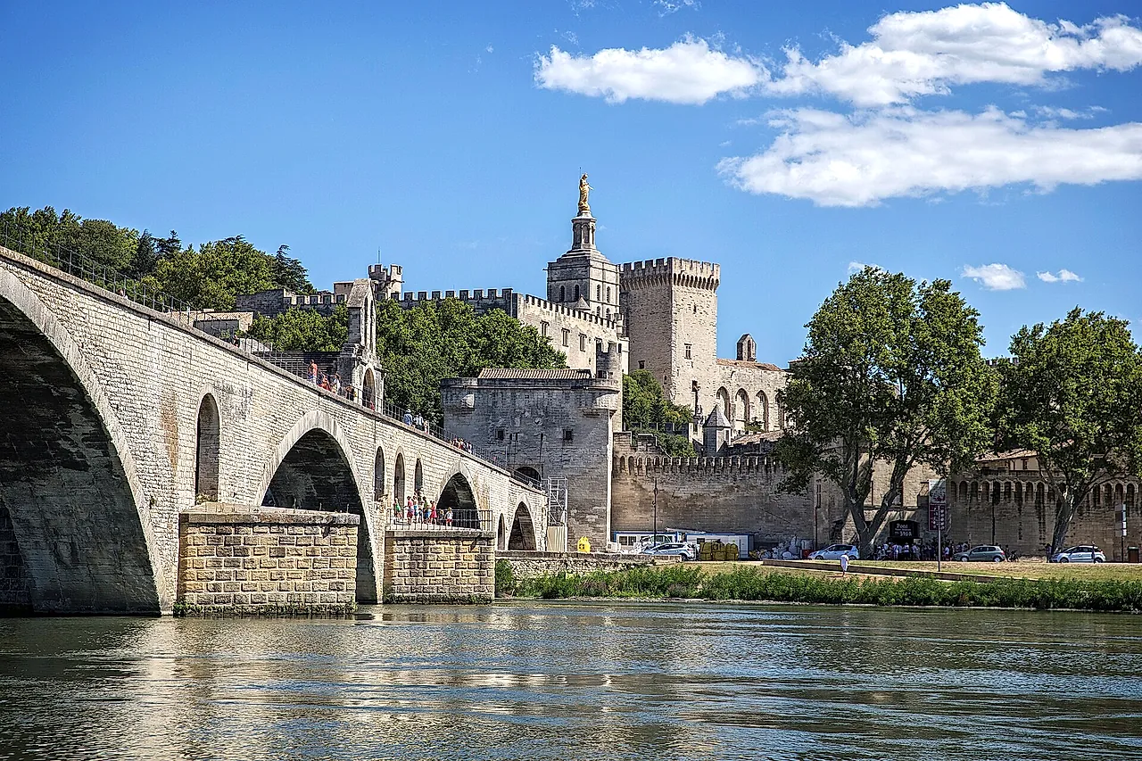 The arches of the Pont Saint-Bénézet over the Rhône, with the towers of the Palais des Papes and the cathedral's golden statue behind the walls