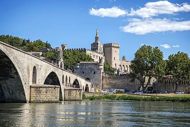 The arches of the Pont Saint-Bénézet over the Rhône, with the towers of the Palais des Papes and the cathedral's golden statue behind the walls
