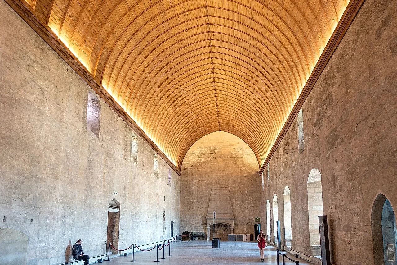 The Grand Tinel of the Palais des Papes, a long hall under a lit wooden barrel vault, with a fireplace at the far end