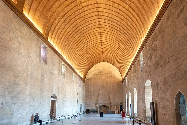 The Grand Tinel of the Palais des Papes, a long hall under a lit wooden barrel vault, with a fireplace at the far end