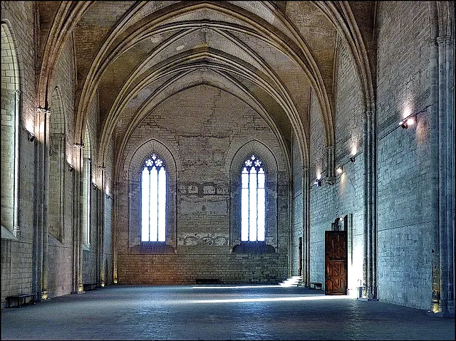The nave of the Grande Chapelle, a very tall Gothic hall with two tall pointed windows and a stone floor