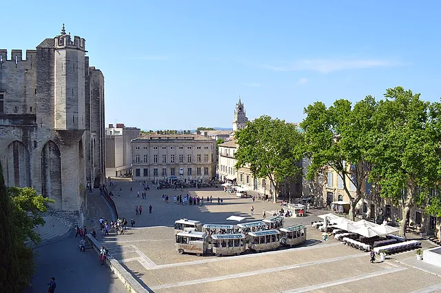 The Place du Palais seen from above, with a tourist road train, plane trees and a palace tower on the left
